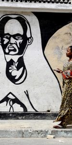 A man walks in front a mural painting of Cheikh As-Saidi Al Hadji Malick Ibn Uthman Ibn Demba Ibn Chamsidine SY, a scholar of the Maliki school of Law and of the Ash'arite theology school, as well as an imam of the Sufi brotherhood Tidjane, on June 29, 2015 in Dakar. Graffiti featuring religious figures, politicians, daily life scenes, as well as Ebola and malaria prevention messages cover the walls of certain streets of Dakar. Written in French or in Wolof, these messages can have educational purposes while others merely contribute to embellish the capital.  AFP PHOTO / SEYLLOU / AFP PHOTO / SEYLLOU